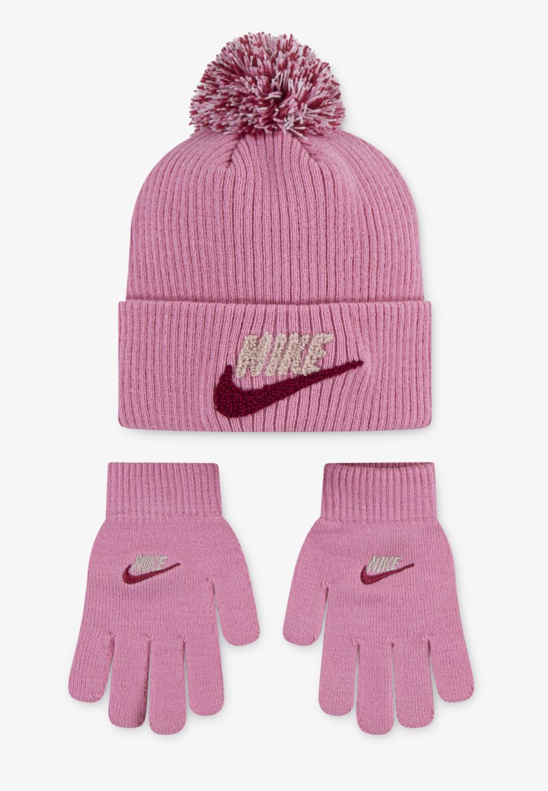 Růžová pletená čepice s bambulí a ohnutým lemem, zdobená texturovaným logem "Nike". Odpovídající růžové pletené rukavice se podobnými akcenty loga.
