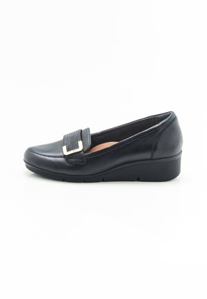 Chaussure noire en cuir à enfiler avec une sangle texturée et une boucle en métal doré, dotée d'une semelle en wedge basse et d'une semelle intérieure rembourrée.