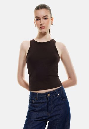 Brown ribbed tank top with a round neckline and slim straps, paired with dark blue high-waisted jeans featuring classic button and pocket details.