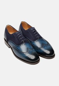 Scarpe oxford in pelle blu navy con dettagli brogue, tomaia in suede e punta lucida. Presentano una finitura blu sfumata e chiusura con lacci.