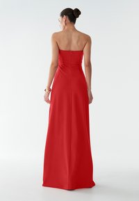 Rode strapless avondjurk met een getailleerde bodice en een sleeprok, voorzien van een ritssluiting en een gladde textuur.