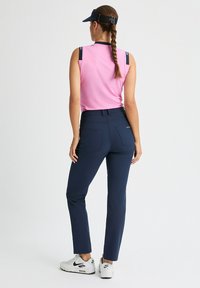 Bezrękawnik w kolorze różowym z granatowymi akcentami, w połączeniu z granatowymi dopasowanymi spodniami. Białe trampki dopełniają strój, prezentując sportowy design.