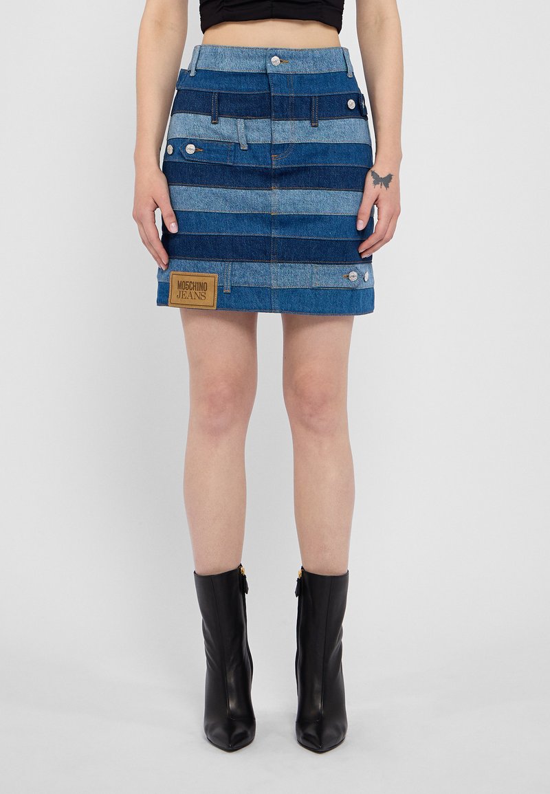 Denim svārki ar maiņām ziliem un gaiši ziliem horizontāliem svītrām, sudraba detaļām un brūnu uzlīmi ar "Moschino Jeans" uz priekša.