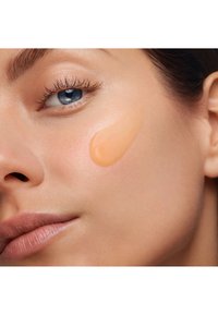 Grunnlag i en ferskenfarge påført huden. Jevn tekstur som fremhever den naturlige teint, med fokus på kinn- og øyeområdet.