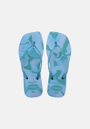 O pereche de șlapi cu model camuflaj albastru și verde, tălpici texturate și barete cu marcă, văzuți de sus pe un fundal alb.