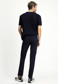 Camisa de manga corta azul marino combinada con pantalones ajustados azul marino y zapatillas grises. Tela suave con costuras mínimas y sin logotipos visibles.