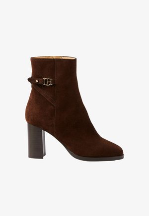 Stivaletto alla caviglia in suede marrone con punta quadrata, tacco a blocco di media altezza e cinturino decorativo con ferramenta metallica sul lato.