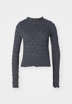 Sötét szürke, hosszú ujjú felső, textúrált mintával, amely a lombozatra emlékeztet. Kerek nyakkivágással és enyhén cropped fazonnal rendelkezik.