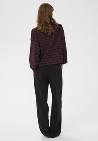 Burgundská pruhovaná nadrozmerná blúzka so širokými rukávmi a okrúhlym výstrihom, kombinovaná s čiernymi nohavicami rovného strihu. Hladká tkanina, voľný strih.
