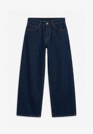 Jean denim bleu foncé à jambes larges avec bouton et fermeture éclair à l'avant, passants pour ceinture, et style cinq poches, posé à plat sur un fond blanc.