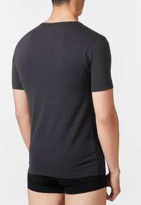 T-shirt nera a maniche corte con design aderente, realizzata in cotone morbido. Tessuto uniforme con scollatura a girocollo e dettagli laterali senza cuciture.