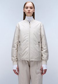 Beige bomberjack met een gladde afwerking, voorzien van een rits aan de voorkant, twee zijzakken, ribgebreide manchetten en een relaxed silhouet.