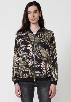 Chaqueta bomber negra con estampado vibrante de hojas en rosa y verde, cierre de cremallera, puños y dobladillo acanalados, fabricada en tejido ligero.