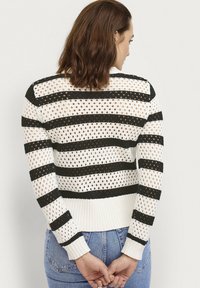Witte en zwarte gestreepte gebreide trui met open geweven ontwerp, ribbelmanchetten en -zoom, met een cropped silhouet en lange mouwen.