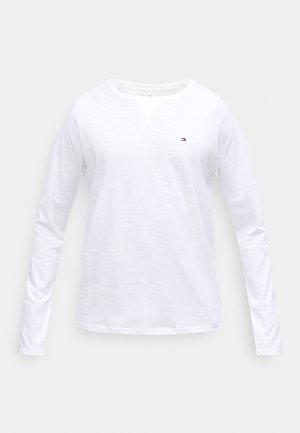 Bílá košile s dlouhým rukávem z měkké látky, s kulatým výstřihem a malým logem na prsou. Standardní střih s hladkou texturou.