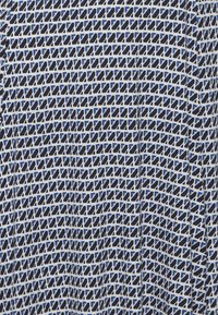 Blå och vit mönstrad tyg med ett rutnät av små rektanglar. Designen har växlande nyanser av blått inom formerna.