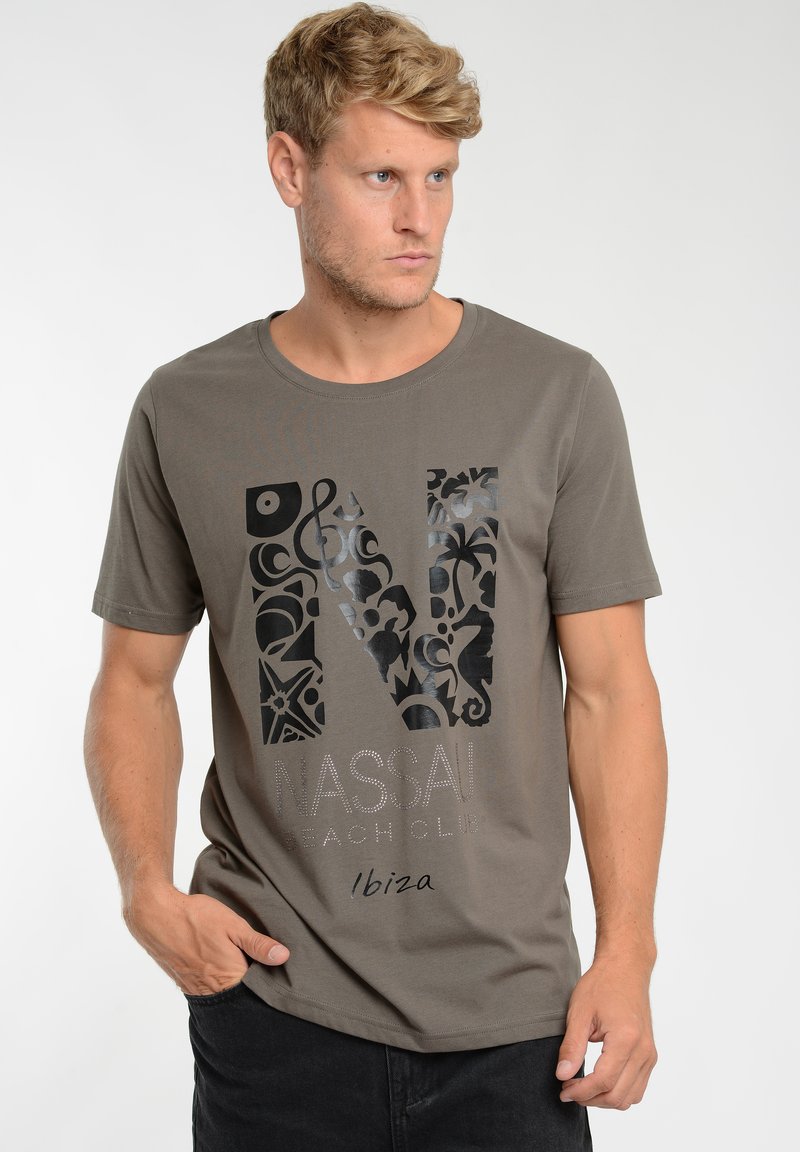 Grey cotton t-shirt with short sleeves, featuring a bold black graphic design of an "N" and decorative patterns. Text reads "NASSAU BEACH CLUB Ibiza."
