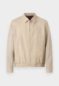 Veste légère beige pour homme avec fermeture éclair sur le devant, col pointu, manches longues, ourlet élastique et poches latérales.