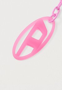 Ružový plastový prívesok na kľúče s štýlovo zobrazeným písmenom „A“ v oválnom obryse, pripevnený k zodpovedajúcemu ružovému reťazcu.