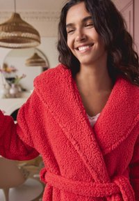 Red fleece robe with a textured surface, wide collar, and belted waist. Features a casual fit and cozy appearance.