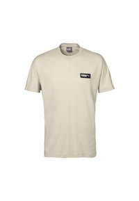 Světle béžové bavlněné tričko s krátkými rukávy, kulatým výstřihem a malou černou obdélníkovou nášivkou na levé části hrudníku.