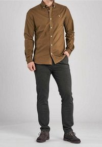 Brown button-up shirt with collar, long sleeves, and logo on chest, paired with dark gray slim-fit pants and brown lace-up shoes.