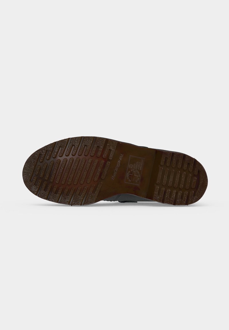 Suola in gomma marrone di una scarpa con profondi motivi del battistrada orizzontali e verticali su sfondo bianco.