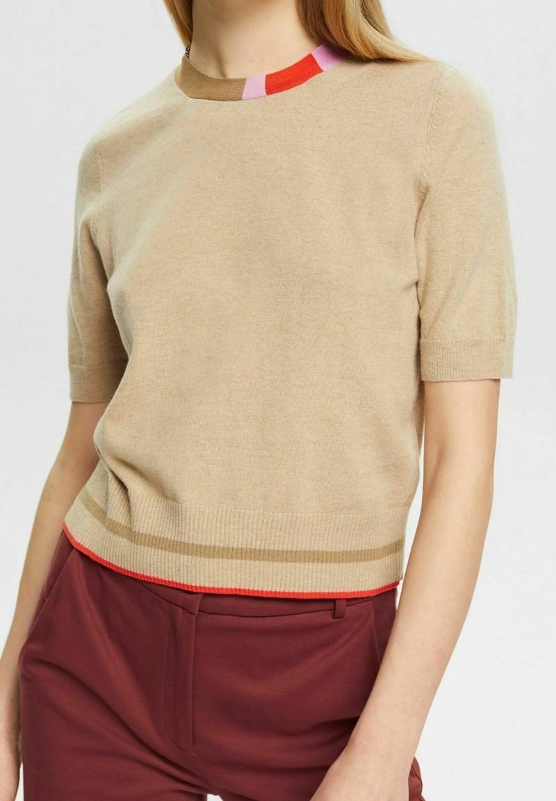 Suéter corto de manga corta beige con un cuello de canalé multicolor que presenta acentos en rosa, rojo y naranja, y un dobladillo inferior en rojo contrastante.