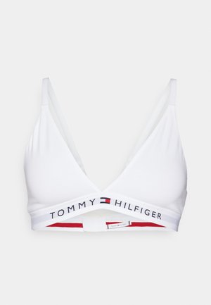Bijela trokutasta bralette s podesivim naramenicama. Traka sadrži "TOMMY HILFIGER" logo u crnoj boji s crvenim i mornarsko plavim detaljima. Mekana, glatka tkanina.