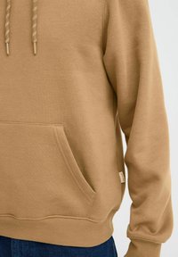 Brown cotton hoodie with a kangaroo pocket, ribbed cuffs, and a drawstring hood featuring textured accents.