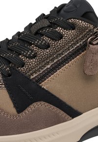 Gros plan d'une basket marron et noire en tissu texturé, avec des lacets noirs épais, une fermeture éclair latérale avec un curseur en daim et une semelle en caoutchouc beige.