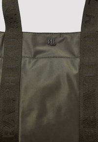 Oliivinvihreä nailoninen olkalaukku, jossa kohoavat "RALPH LAUREN" -hihnat ja metallinen logokoriste. Sileä pinta ja minimalistinen muotoilu.