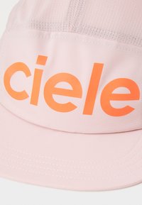 Roze pet van zacht stof met een groot oranje "ciele" logo op de voorkant. Bevat stiksels en een gebogen vizier.
