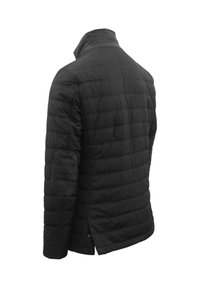 Giacca nera trapuntata con colletto alto, caratterizzata da tessuto strutturato, cuciture diagonali e toppine sui gomiti, progettata per calore e comfort.