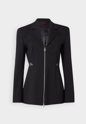 Black blazer with a sharp collar, front zipper, fitted design, and mesh side accents. Smooth fabric with a subtle inner pattern.