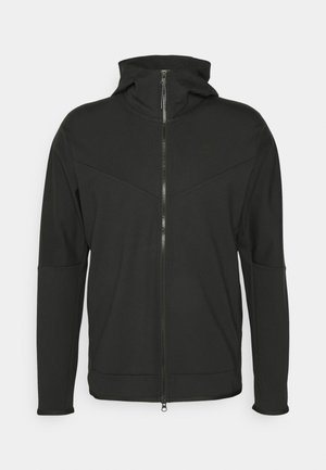Schwarze Zip-up-Hoodie mit hohem Kragen, aus glattem Stoff gefertigt. Verfügt über ein diagonales Nahtdesign und ein dezentes Logo auf der Brust.