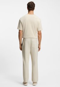 Hellbeige Kurzarm-Oberteil mit lockerem Sitz und passenden Hosen mit Gesäßtasche, aus weichem Stoff gefertigt, für Komfort entworfen.