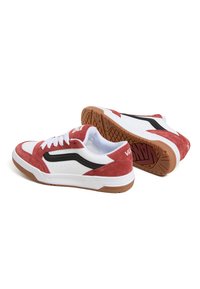 Røde ruskinds- og hvide lædersneakers med sorte detaljer, snørebånd og en gummisål; har perforeringer og Vans-logo på hælen.
