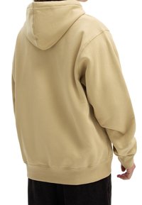 Felpa con cappuccio beige dal taglio morbido, polsini e orlo a coste. Tessuto liscio, cuciture minime e senza loghi o motivi visibili.