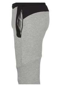 Grijze sportieve joggers met een zwarte, geribbelde tailleband. Beschikt over een zijzak met rits en schuin gestikte naden voor een moderne pasvorm.