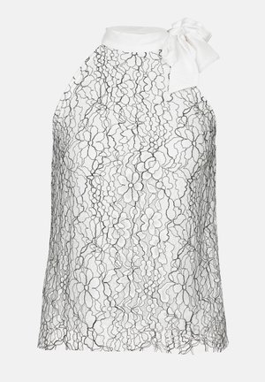 White blouse with black floral lace overlay, halter neck design with a bow detail at the shoulder and scalloped hem. Soft texture.