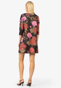 Schwarzes Blumenkleid mit Dreiviertelärmeln, verziert mit großen roten und rosa Rosen sowie grünen Blättern. Glatte Stoffqualität, knielanges Design.