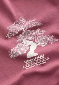 Rosa Stoff mit einer weißen Grafik eines Baumes und dem Text "Suzhou-Gärten, Provinz Jiangsu" und "Die Welt hat viel zu sagen."