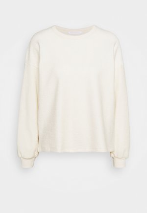 Sudadera de color crema hecha de un tejido texturizado, con mangas largas, cuello redondo y puños acanalados, con un diseño de corte relajado.