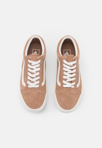 Hnědé semišové tenisky s bílými tkaničkami a bočními pruhy, s nízkým designem a kulatou špičkou. Texturovaný svršek a gumová podrážka.