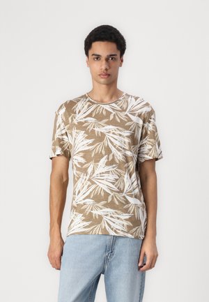Camiseta marrón de manga corta con un patrón de hojas blancas. Tejido suave con un corte relajado, cuello redondo y mangas ligeramente enrolladas.