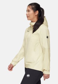 Helle gelbe wasserdichte Jacke mit Reißverschluss, Kapuze und Seitentaschen; verfügt über ein Logo-Patch am Ärmel und eine glatte, leichte Textur.