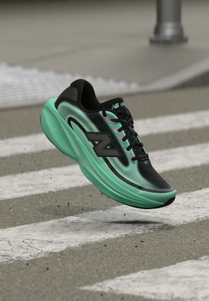 Chaussure de course New Balance noire et turquoise en suspension au-dessus d'un passage piéton d'une rue de la ville avec la chaussée et le trottoir en arrière-plan.