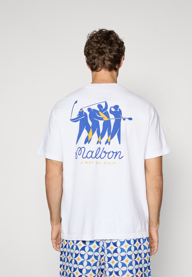 Hvid bomulds t-shirt med et blåt og gult grafisk design af fire figurer, der spiller golf, med teksten "Malbon" og "L'Art Du Coup" nedenfor.