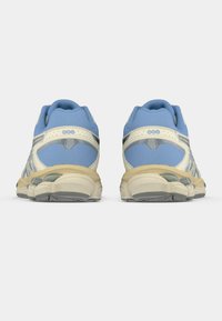 Μπλε δίχτυνα αθλητικά παπούτσια με κρεμ λεπτομέρειες και υφασμάτινες σόλες από καουτσούκ, διαθέτοντας σύστημα απορρόφησης κραδασμών GEL και επενδεδυμένο κολάρο για στήριξη.